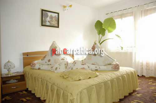 Imagine dormitor cu pat matrimonial la pensiunea Orhidea din Ceahlau cu ferestre largi si cu lumina abundenta