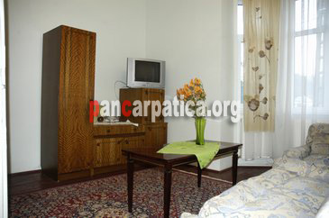 Imagine cu interiorul unui dormitor cu tv cu ferestre largi orientate catre curtea spatioasa din pensiunea La Gorita-Vama