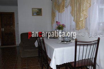 Imagine living cu mese si scaune din lemn, in interiorul pensiunii Emilia din Sucevita