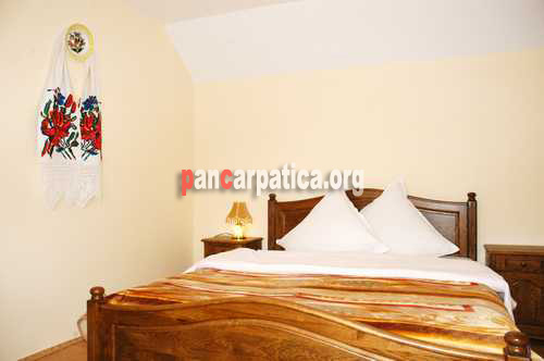 Imagine cu interiorul dormitorului cu ferestre mari luminoase, cu pat matrimonial comod din Casa Bobocea-Poienile Izei