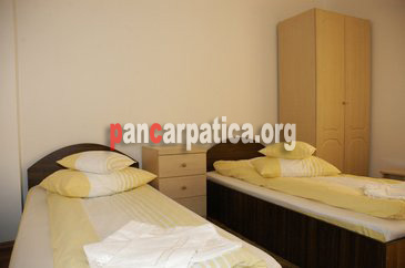 Imagine dormitor spatios cu 2 paturi simple curate si elegante in pensiunea Casa Bucovineana din Vatra Dornei