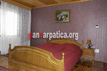 Imagine camera cu pat matrimonial mare si elegant in interiorul pensiunii Casa dintre Pini din Agapia