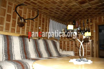 Imagine interior cu canapele imbracate cu cergi, exponate vanatoreti pe perete la pensiunea Csa Cristi din Sucevita