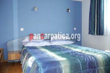 Imagine a dormitorului cu pat matrimonial confortabil din pensiunea Codrii de Arama-Varatec