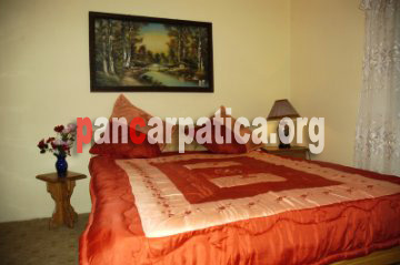 Imagine dormitor elegant cu pat matrimonial curat in pensiunea Trifoi Parasca din Botiza