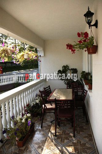 Imagine cu balcon elegant si bine echipat cu scaune, masa si flori multe si viu colorate in pensiunea Alex din Manastirea Humorului