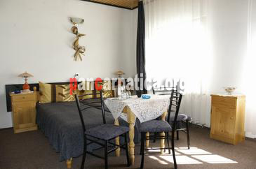 Imagine camera cu 2 paturi simple comode, masa si scaune din lemn in pensiunea Orizont din Farcasa