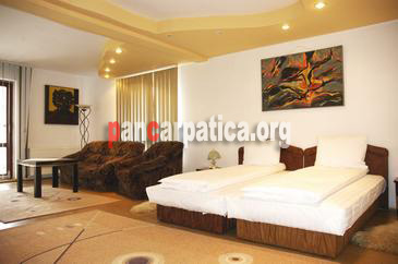 Imagine camera cu 2 paturi simple comode, canapea si fotolii confortabile, mobila eleganta in interiorul Vilei Camelia din vatra Dornei