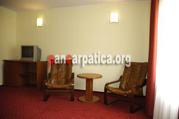 Imagine cu interiorul din pensiunea Vanatorul-Vatra Dornei cu tv, masa si scaune din lemn, canale tv