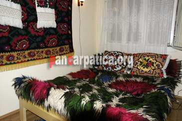 Imagine a dormitorului rustic cu pat dublu confortabil din pensiunea Sub Cetate la Matei-Oncesti