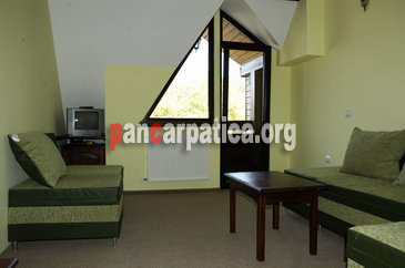 Imagine mansarda cu sofa comoda si fotolii confortabile, tv, masa din lemn, in interiorul pensiunii Musatini din Putna