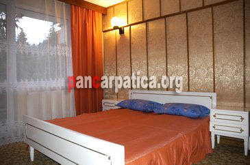 Imagine a dormitorului cu pat matrimonial din Hotel Alex-Campulung Moldovenesc cu ferestre luminioase si mari care sunt orientate spre munti
