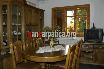 Imagine a livingului interior al pensiunii Casa Aura din Voronet cu masa si scaune din lemn, si mobilier modern