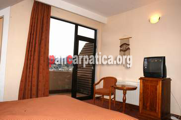 Imagine cu interiorul unui dormitor cu pat matrimonial cu balcon cu vedere spre munti din Vila Ecotur-Ceahlau