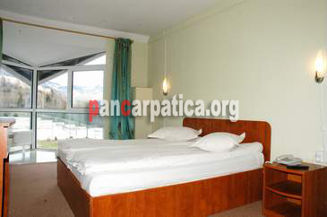 Imagine dormitor spatios si bine dotata cu mobilier modern cu pat matrimonial din Vila Ecotur-Ceahlau