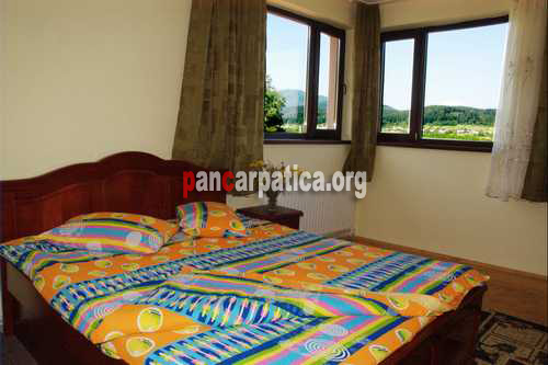 Imagine cu interiroul unui dormitor spatios cu pat matrimonial mare si curat din Cabana Poiana-Putna